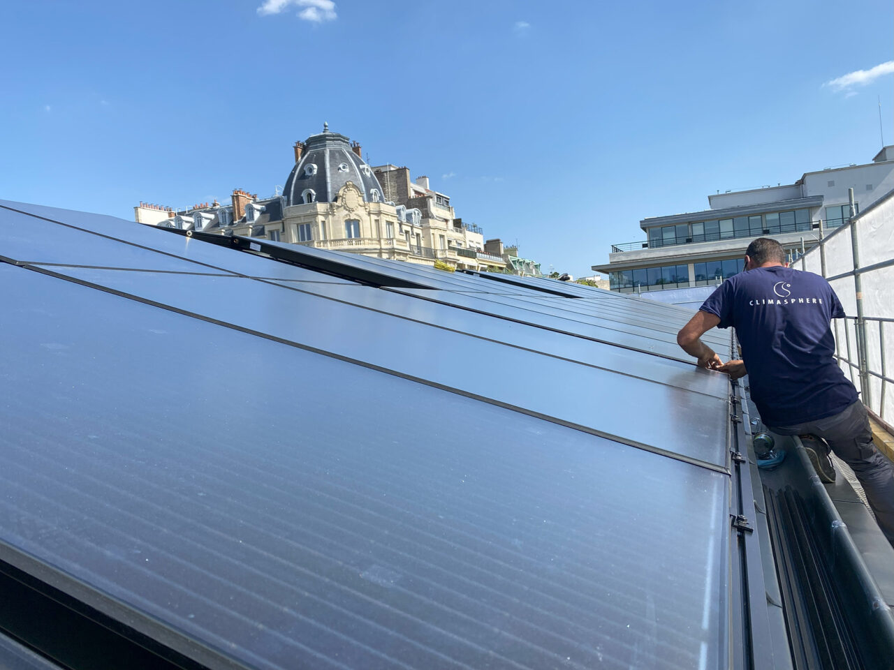 Installation de panneaux solaires photovoltaïques sur un toit, offrant une vue panoramique des toitures environnantes